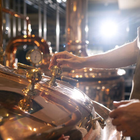 An employee monitoring a unit within a whisky production facility